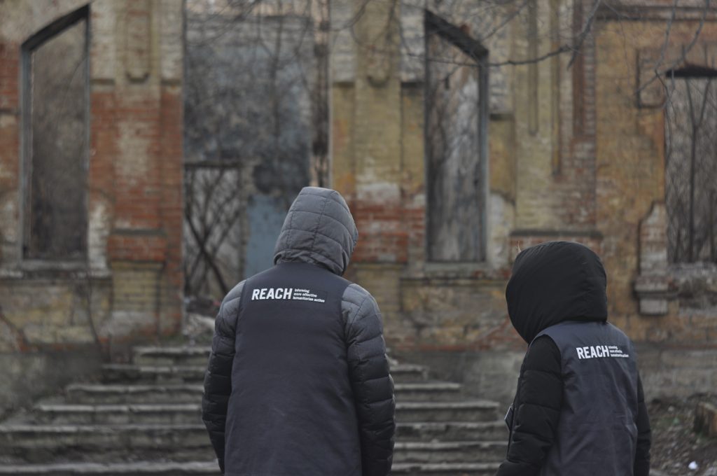 REACH Assessment Officers stand in front of the remains of a shelled building in the community of Verkhnotoretske within 5 km of the line of contact between Ukrainian armed forces and separatist groups ©REACH/2018